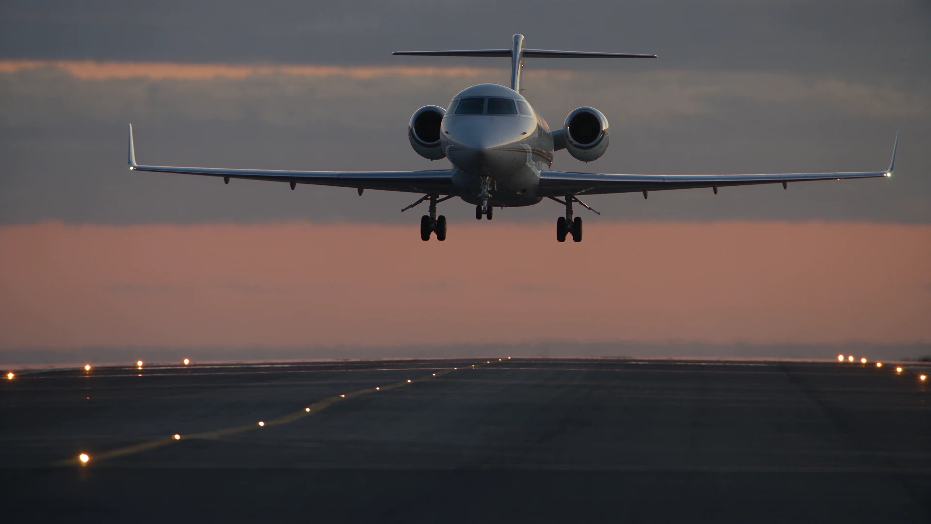 Private jet descending onto the runway, touching down and continuing its rollout